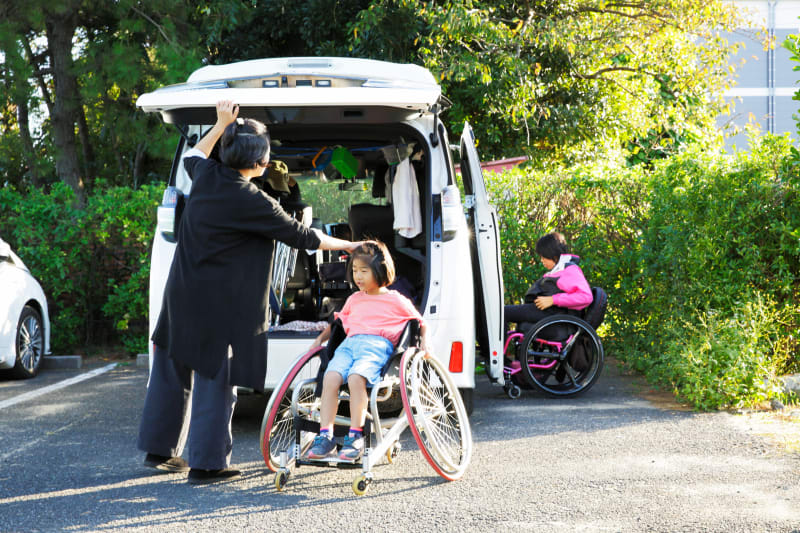 Caretaker helping Children in wheelchair into van.