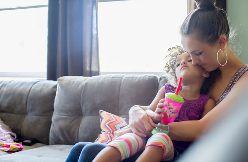 Mother sitting on couch and holding her tired child.