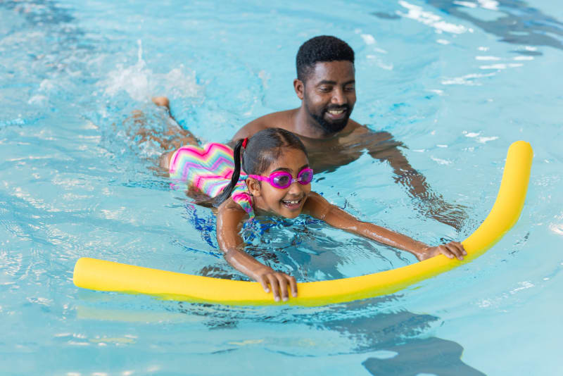 Child and father swimming in pool