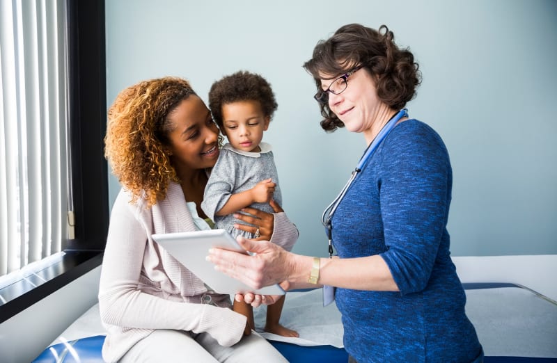 Doctor talking to parent and toddler at medical clinic.