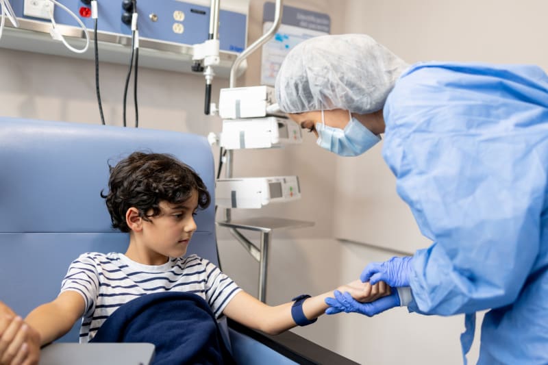 Nurse preparing IV for young boy's chemotherapy treatment. 