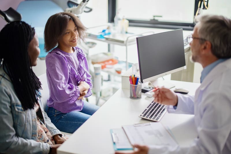 Doctor speaking with teenager and parent.