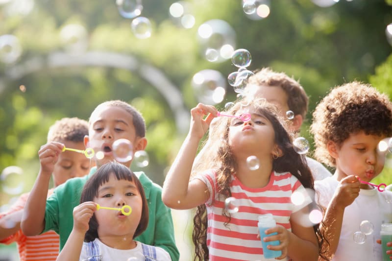 Group of school age children blowing bubbles outside. 