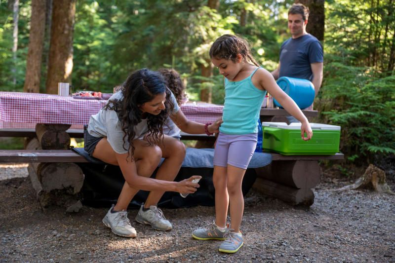 Parent spray insect repellent on child.