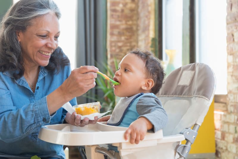 Grandmother feeding Toddler lunch.