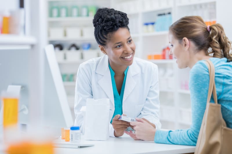 Young female talking to pharmacist about medication.