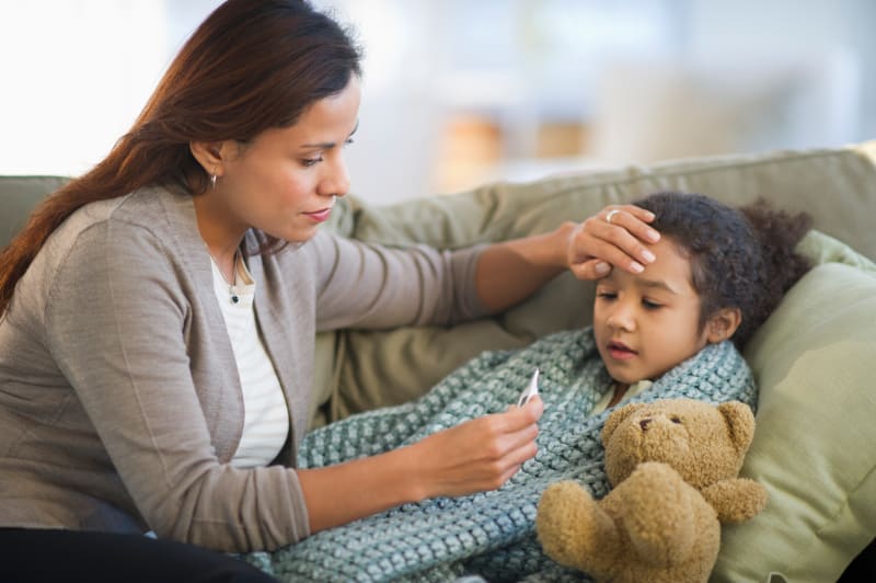 Mother checking child's temperature with thermometer