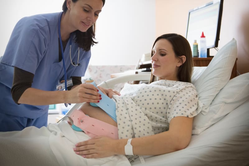 A nurse attaching a fetal monitor to a woman in labor.