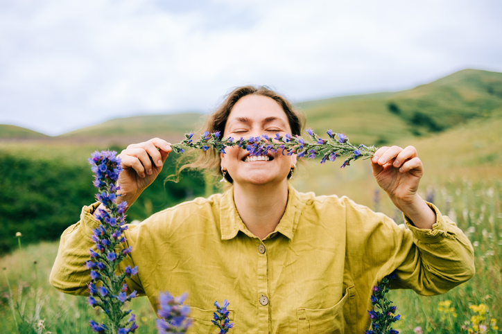 Woman outside in field smiling while holding lavendar to her face