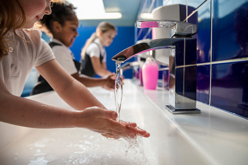 Children washing hands at school bathroom sink