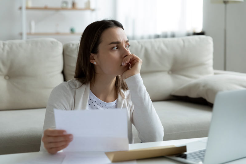 Thoughtful young woman holding paper letter.