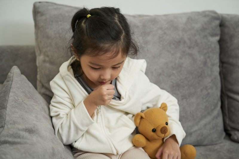 Unwell Toddler girl coughing from sore throat flu and cold.