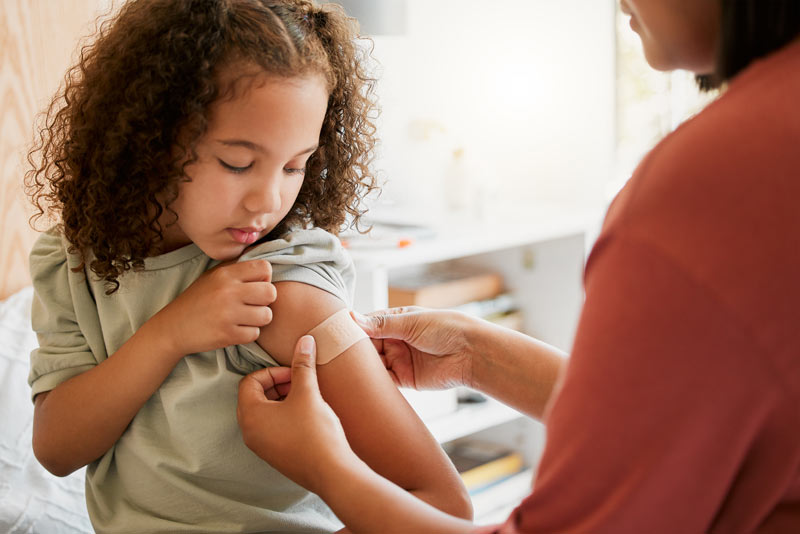 Nurse applying band-aid on girl after an injection.