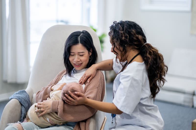 New mother learning to breast-feed with help from lactation consultant.
