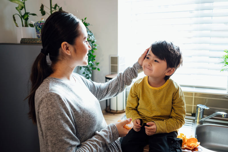 Mother examining son's face sitting on a kitchen counter.