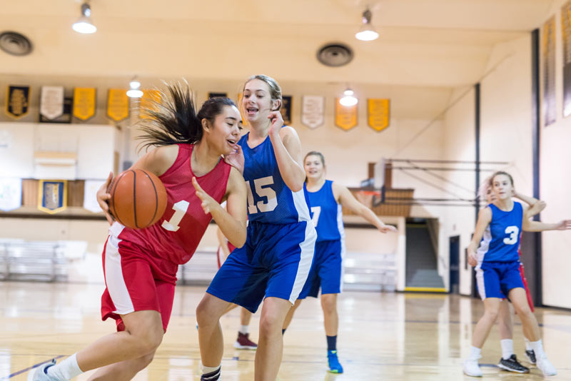 Group of girls playing basketball in a gym.